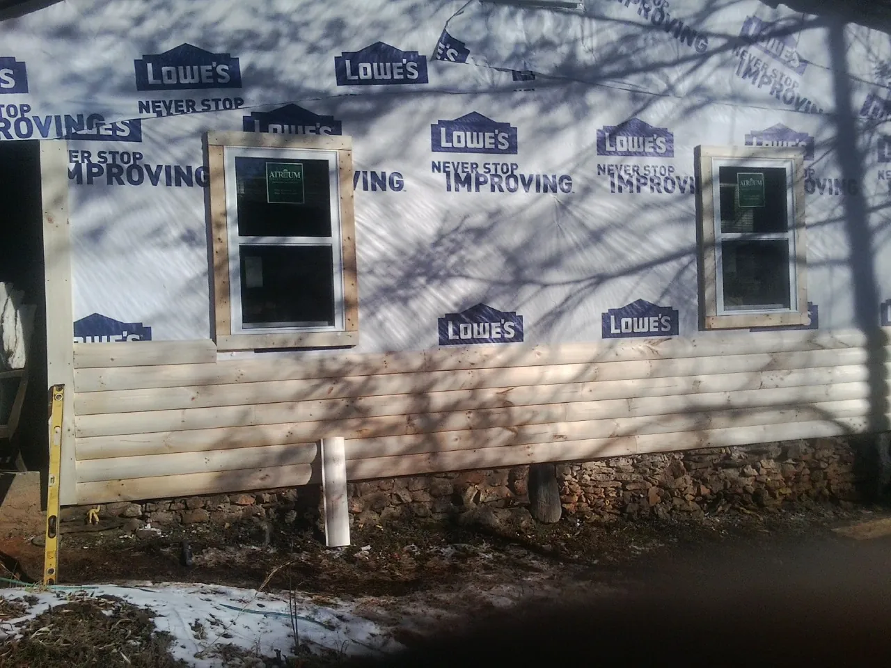 House wrap and new log siding going up on an exterior wall in Paxico