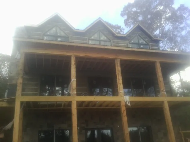 Dormers and porch framing on a large log home under construction — Roof Coating work by our crew in Paxico
