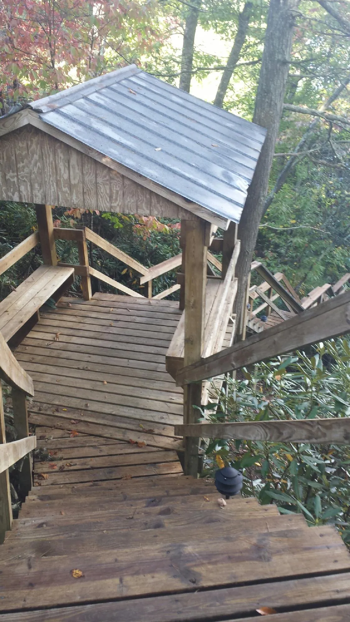 Metal roofed shelter over wooden steps on a wooded walkway — Skylight Repair & Installation work by our crew in Paxico