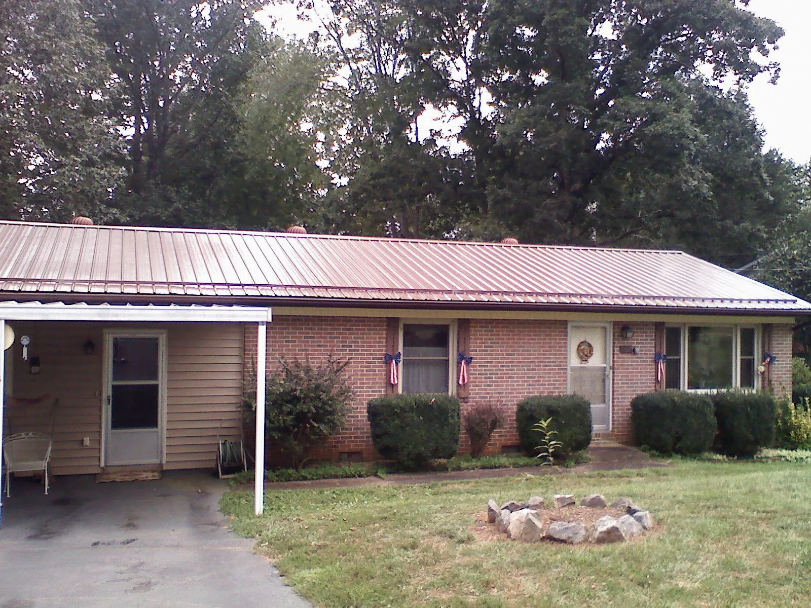 Bronze metal roof and carport on a brick ranch home — Roof Repair work by our crew in Paxico