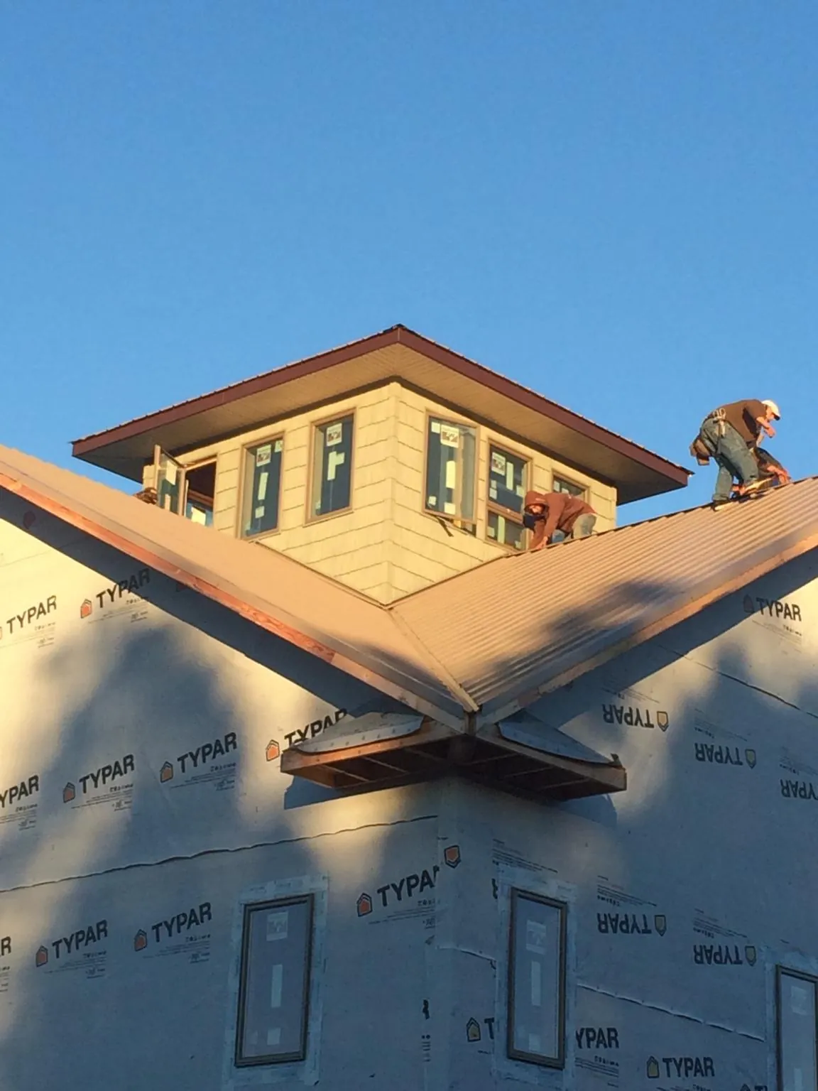 Roofers working around a rooftop cupola on a new metal roof at sunset — Roof Waterproofing in Paxico by Roofing Brothers